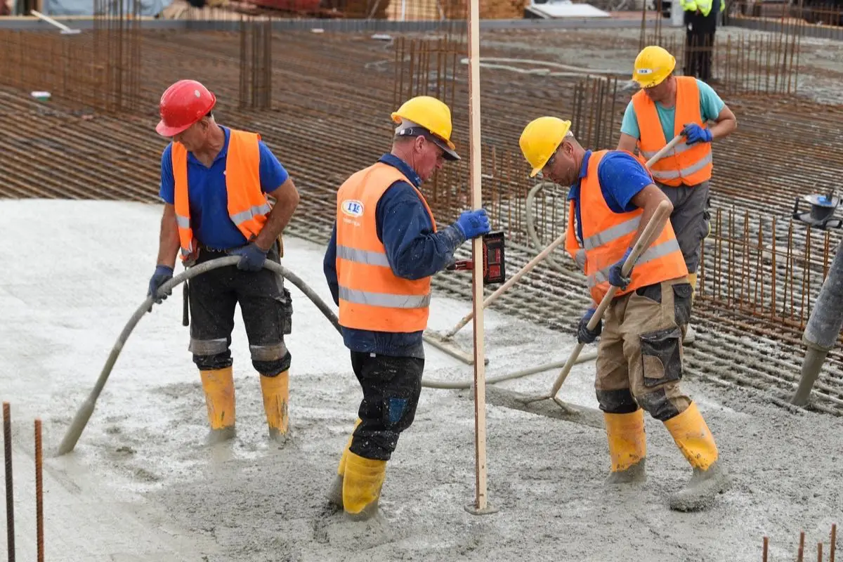 Građevinski radnici ugrađuju i zbijaju beton na armiranoj ploči